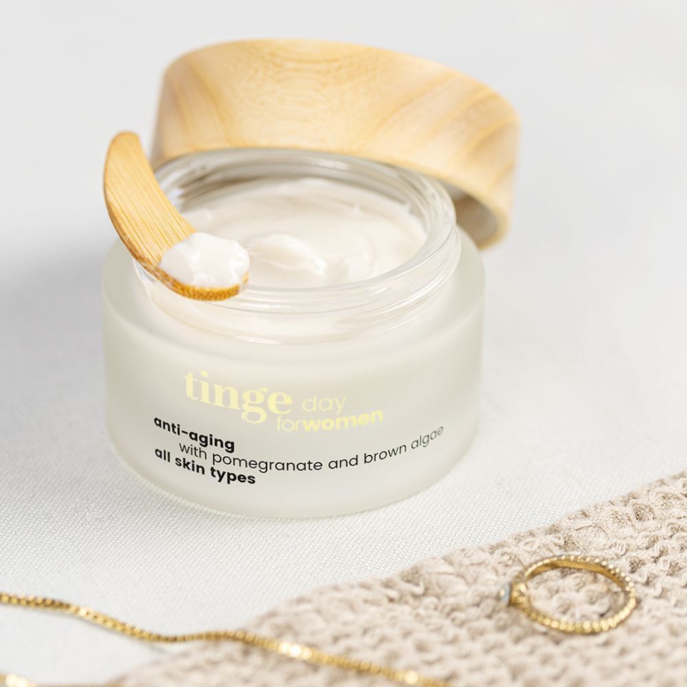 Tinge dagcrème voor vrouwen. Glazen pot met houten deksel. Opschrift: Anti-aging, granaatappel en bruine algen, alle huidtypes.