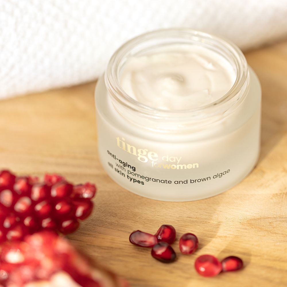 Tinge dagcrème voor vrouwen. Glazen pot met houten deksel. Opschrift: Anti-aging, granaatappel en bruine algen, alle huidtypes.