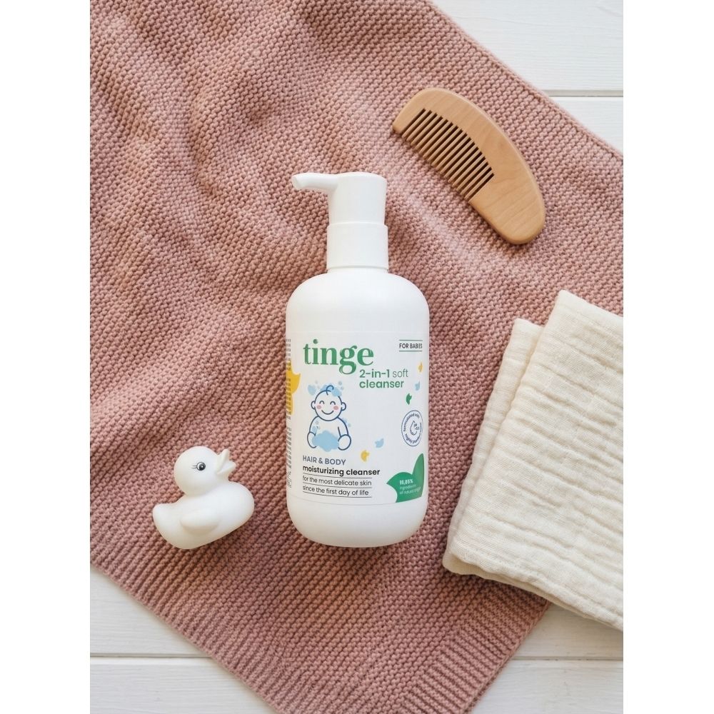 Witte fles met pomp. Opschrift: Tinge, 2-in-1 reinigingsgel. Naast baby-illustratie.