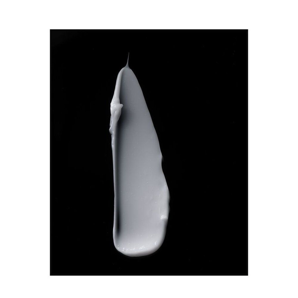 Échantillon de crème blanche sur fond noir. Texture lisse. Pas d'informations sur le produit visibles.