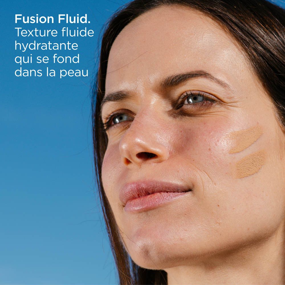 Gros plan sur une femme avec des zones de peau teintées. Texte: Fusion Fluid. Texture fluide hydratante qui se fond dans la peau.