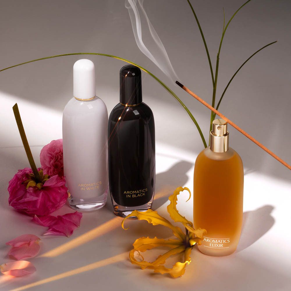 Trois flacons de parfum Clinique Aromatics Elixir, dont un brûle.