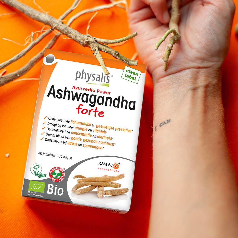 Verpakking van physalis® Ashwagandha forte in hand. Achtergrond met takken. Bevat 30 tabletten. Bio-label.