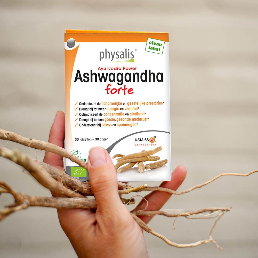 Verpakking van physalis® Ashwagandha forte in hand. Achtergrond met takken. Bevat 30 tabletten. Bio-label.