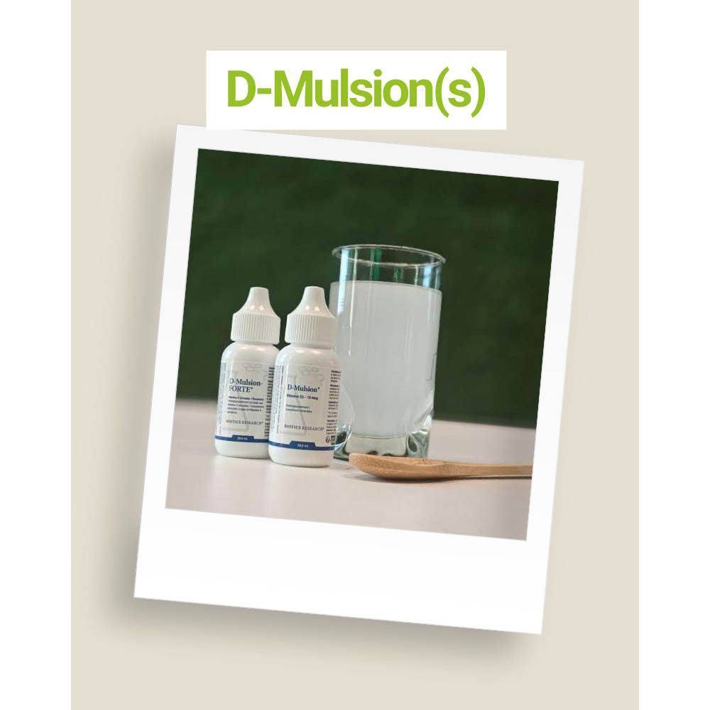 Twee flessen D-Mulsion Forte naast een glas. Op een houten lepel.