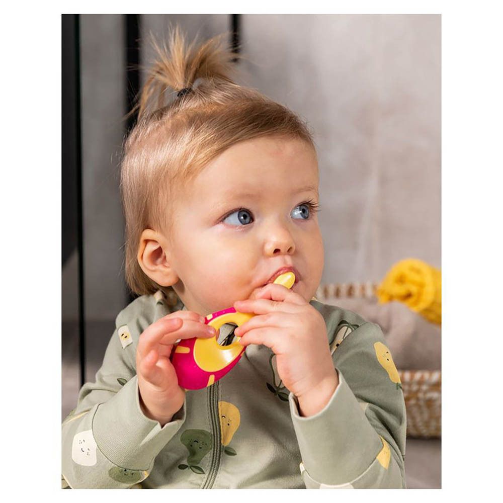 Bébé avec brosse à dents rose et jaune dans la bouche. Bébé tenant la brosse. Manche jaune.