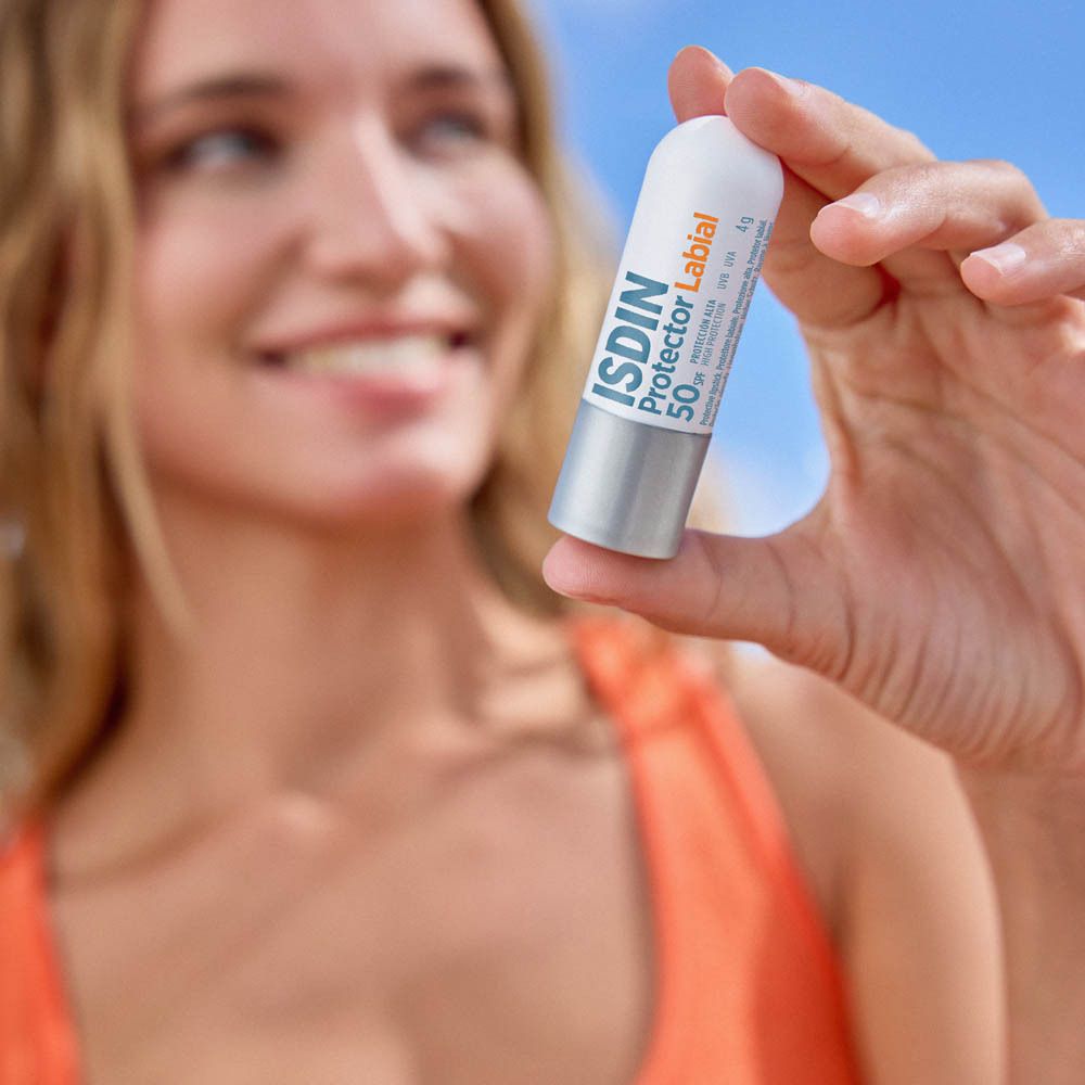 Stick lèvres ISDIN Protector Labial LSF 50+. Blanc et argent. Femme le tient.