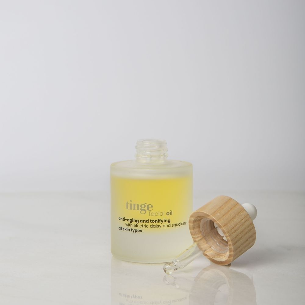 Flacon avec pipette, bouchon à côté, huile visage Tinge.