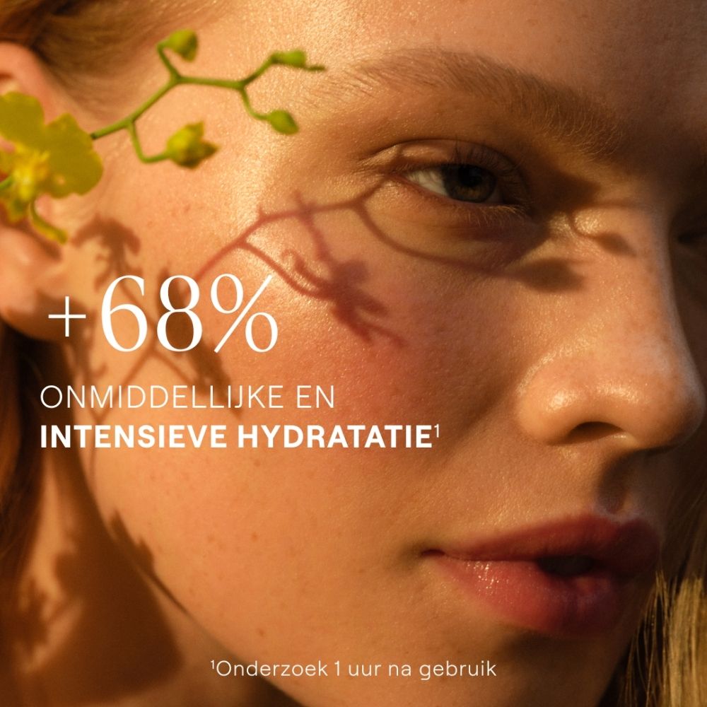 Close-up van een vrouw met een zachte huid en een gele bloesemtak. Tekst: +68% ONMIDDELLIJKE EN INTENSIEVE HYDRATATIE.
