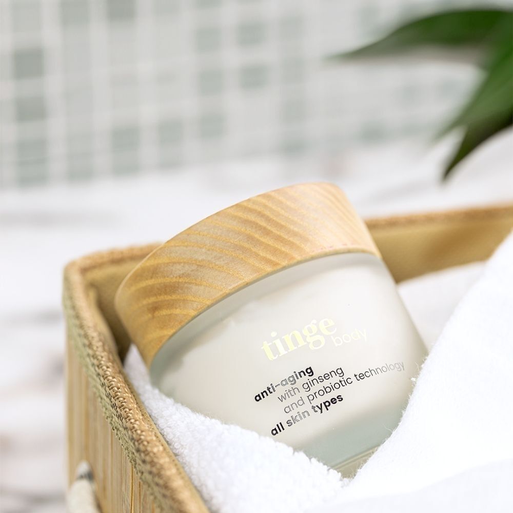 Tinge Bodylotion Anti-Aging in een mandje met een handdoek.