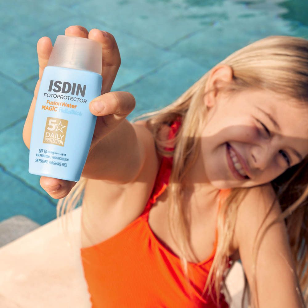 Enfant tenant ISDIN FusionWater. Flacon bleu. Enfant souriant au bord de la piscine.
