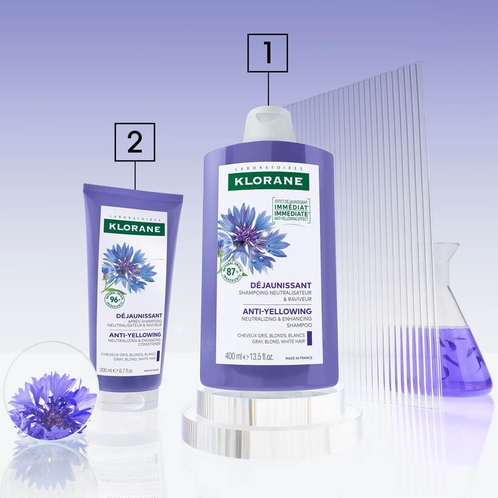 Productopstelling: shampoo fles, tube, korenbloemen. Tekst: Klorane, anti-vergeling shampoo.