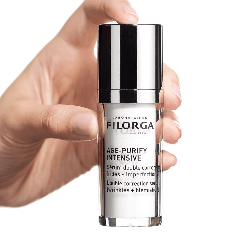 Main tenant le flacon FILORGA Age-Purify Intense Serum. Texte: Sérum double correction.