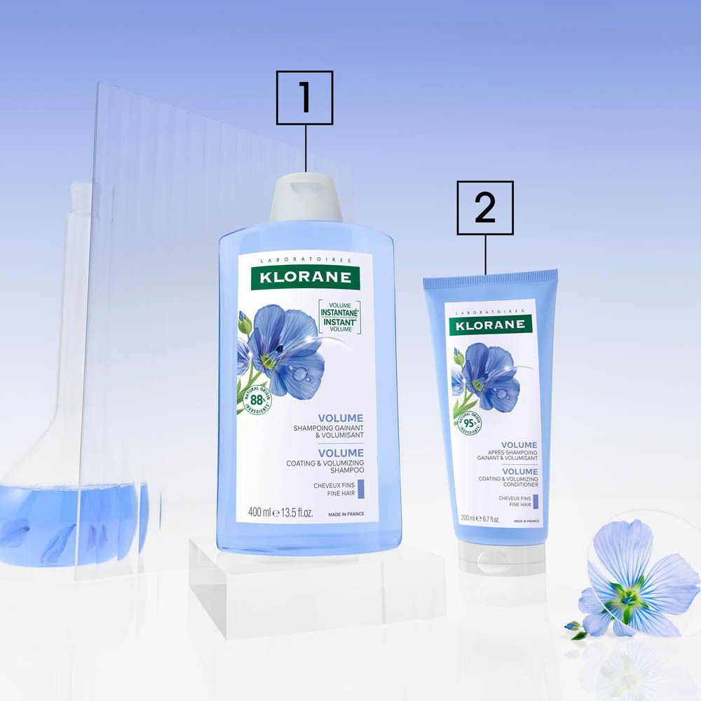 Deux produits Klorane. 1: Shampooing. 2: Après-shampooing. Flacons bleus, bouchons blancs. Fleurs de lin.