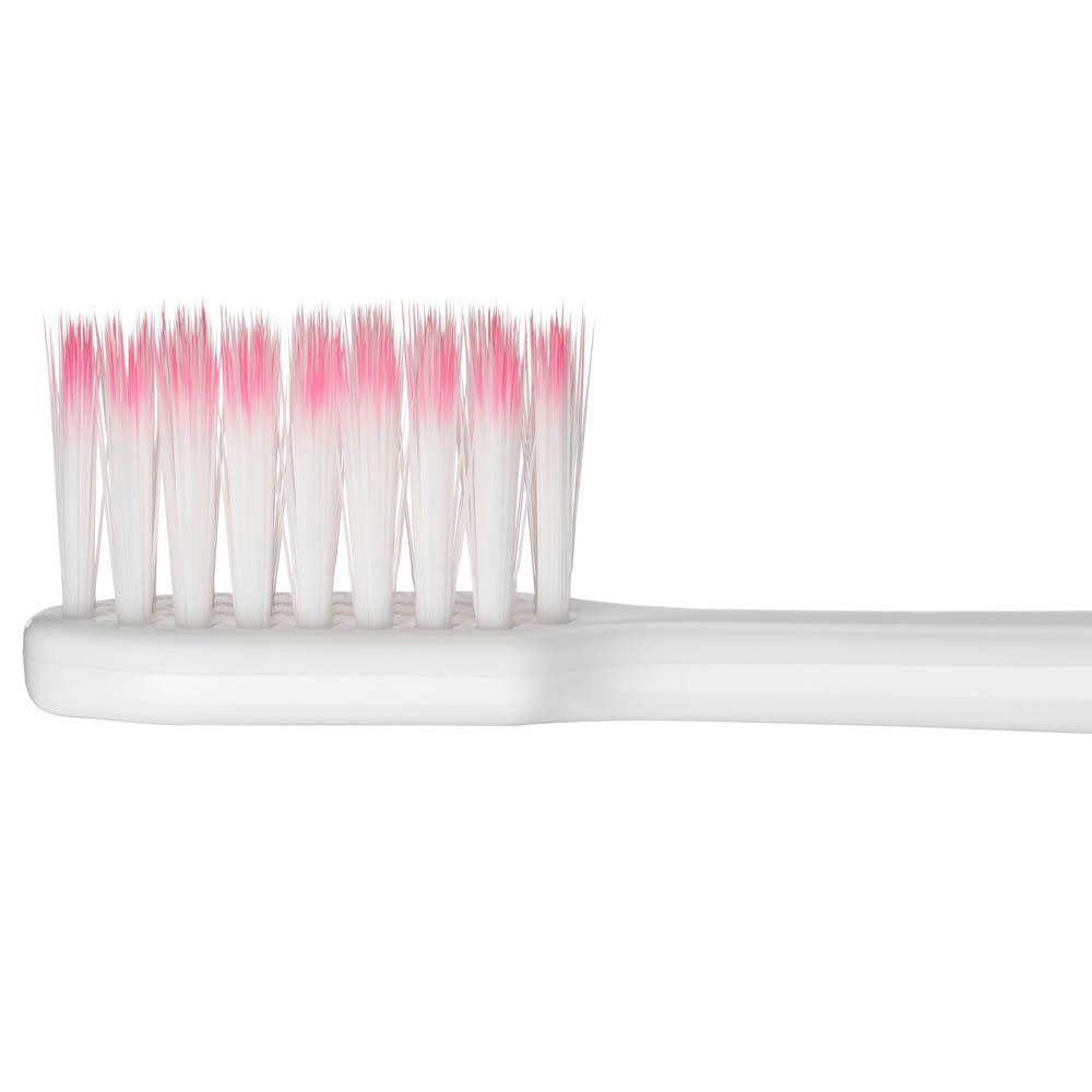 Gros plan des brins d'une brosse à dents G.U.M. Sonic Sensitive. Brins blancs avec pointes roses.