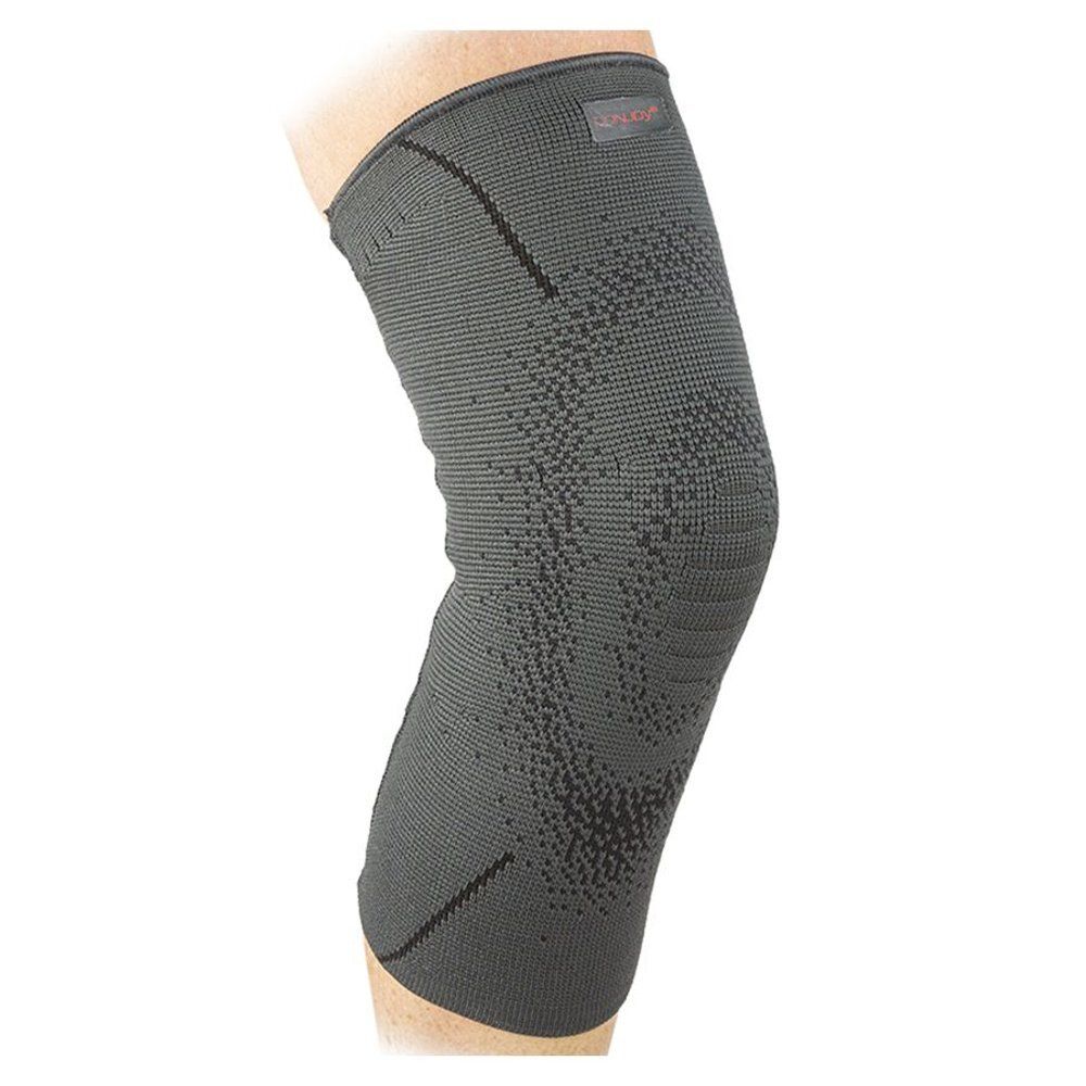 Grijze kniebrace op been. Elastisch materiaal met ingeweven patronen. Merk DonJoy zichtbaar. Extra Extra Large.