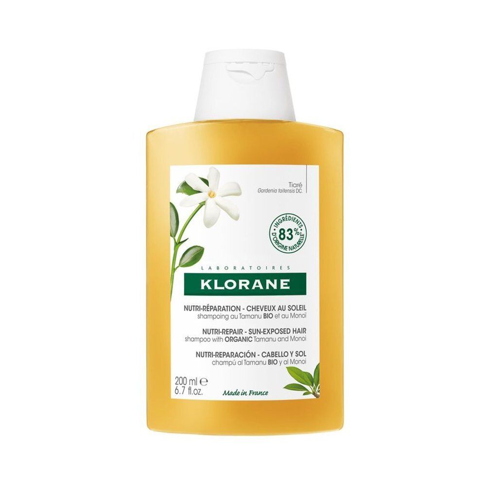 Geelachtige shampoo fles met witte dop. Opschrift Klorane, Nutri-Réparation, Cheveux Soleil, Shampooing au Tamanu Bio et au Monoï. 83% ingrediënten van natuurlijke oorsprong.