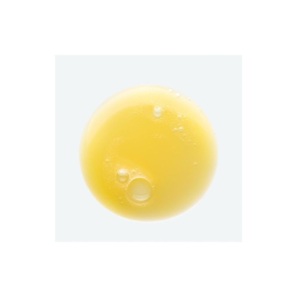 Liquide jaune avec des bulles sur fond blanc. Le liquide est probablement un shampooing ou un produit similaire.