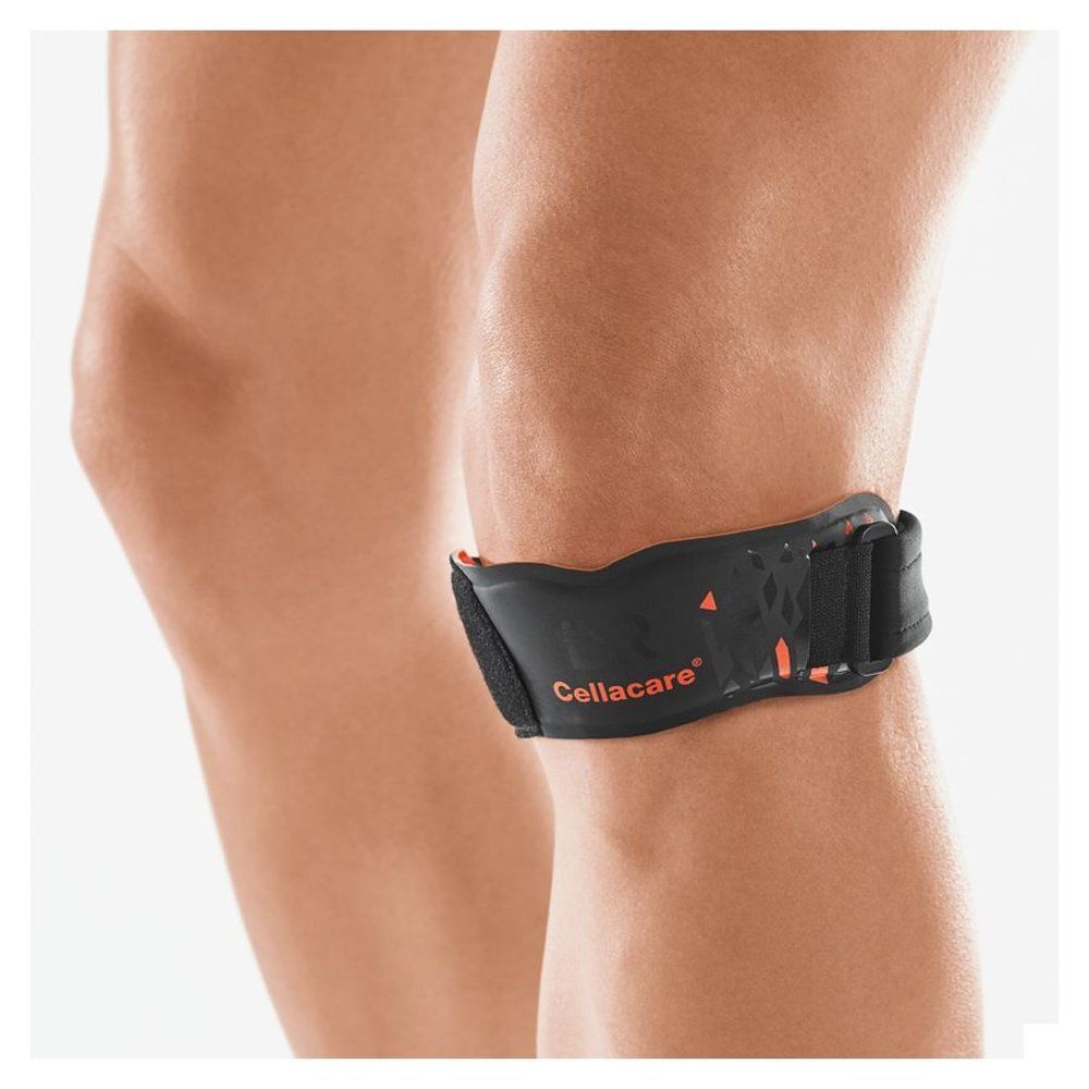 Kniebrace op been. Zwarte band met oranje details en Cellacare-logo.