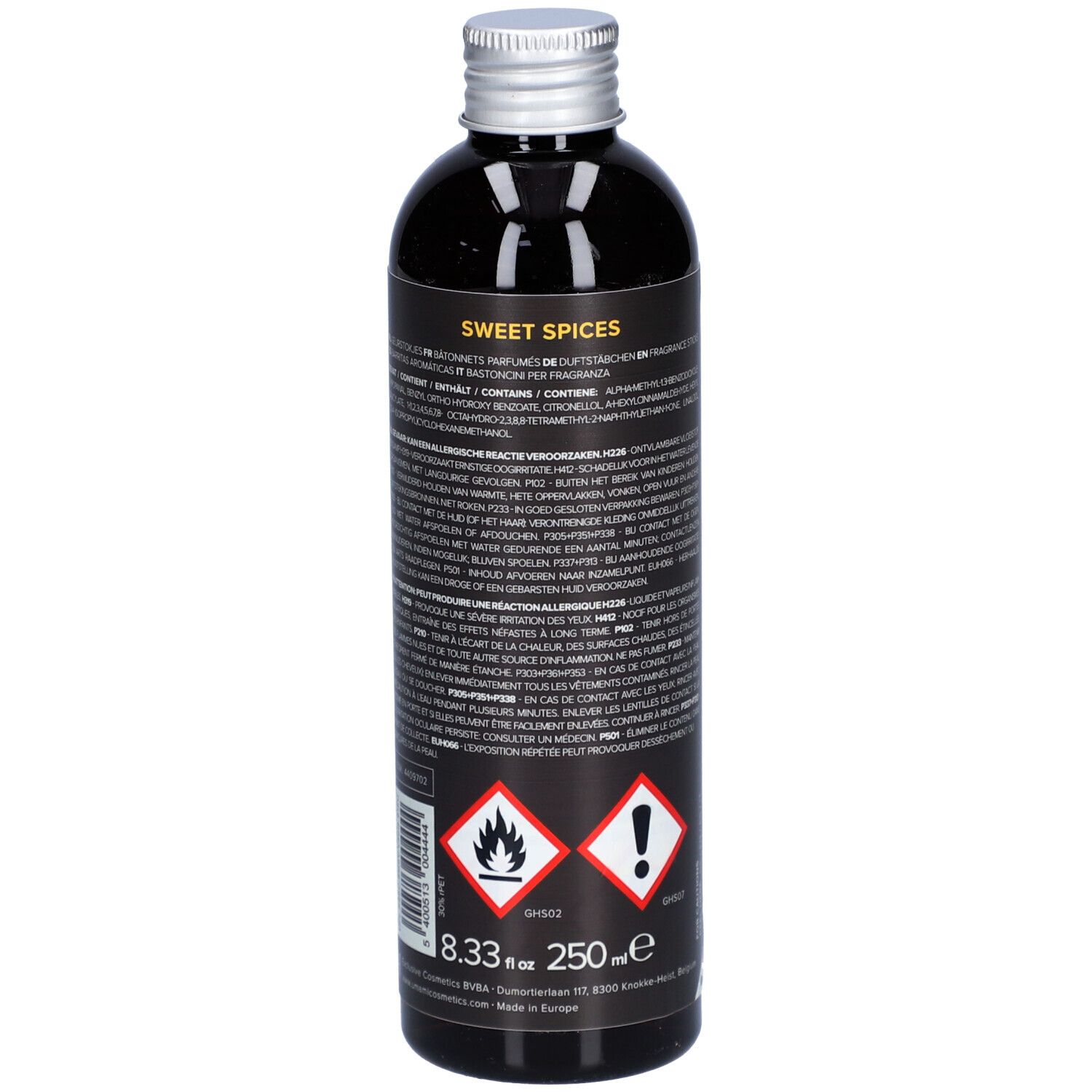 Donkere fles met zilveren dop. Etiket met tekst en gevaarsymbolen. Opschrift: Sweet Spices, 8.33 fl oz, 250 ml.