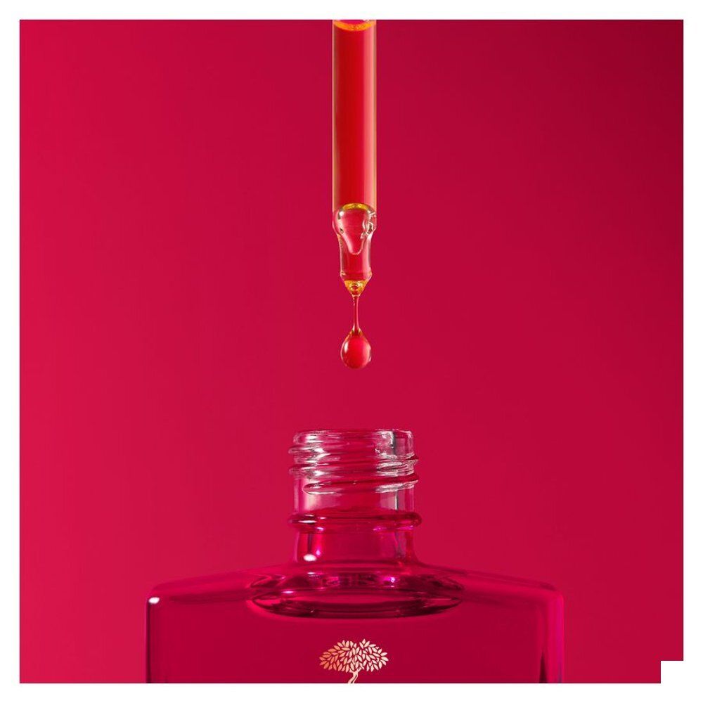 Vrouw houdt Nuxe Merveillance Lift fles en serumdruppelaar vast.