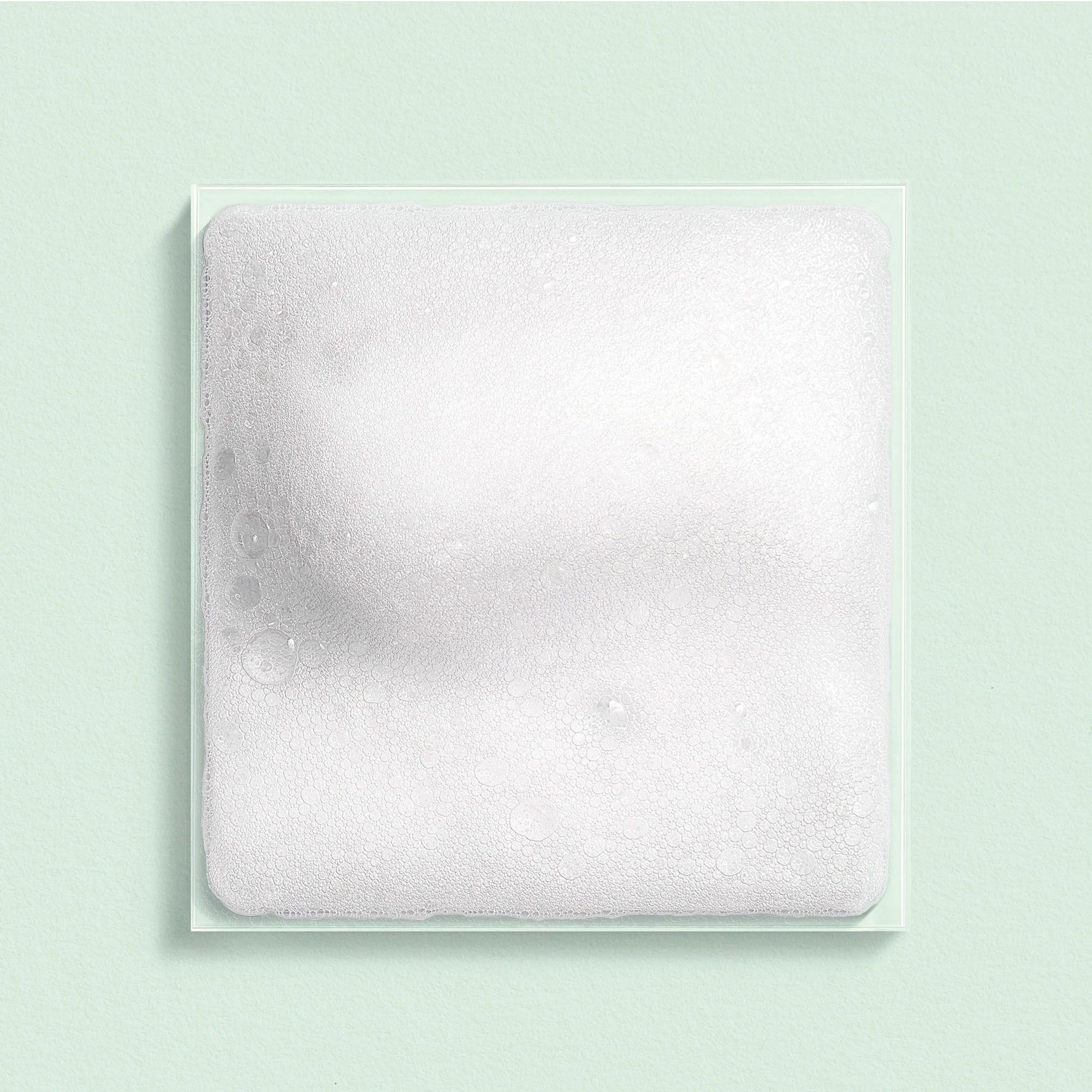 Échantillon de mousse carrée sur fond vert clair. Structure de mousse blanche.