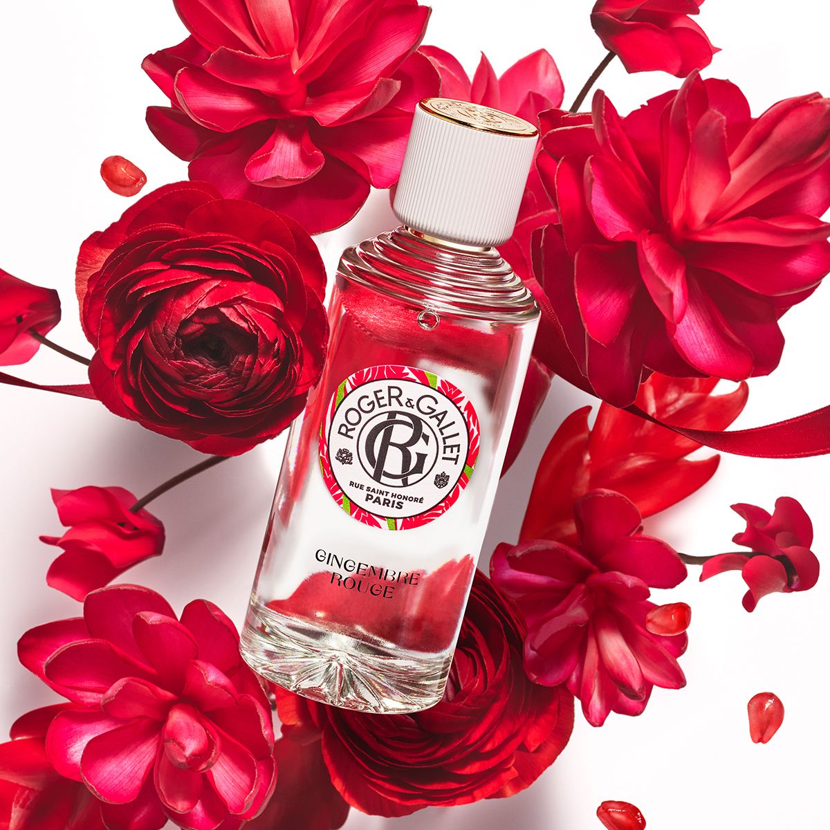Fles met witte dop en gouden ring, omringd door rode bloemen. Tekst: Roger & Gallet, Gingembre Rouge.