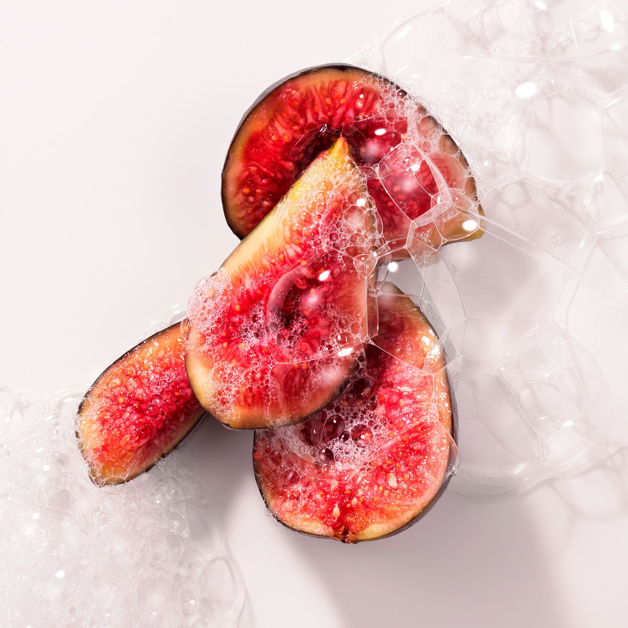 Gros plan de morceaux de figues dans des bulles de savon. Morceaux de fruits rouges avec des bulles blanches.