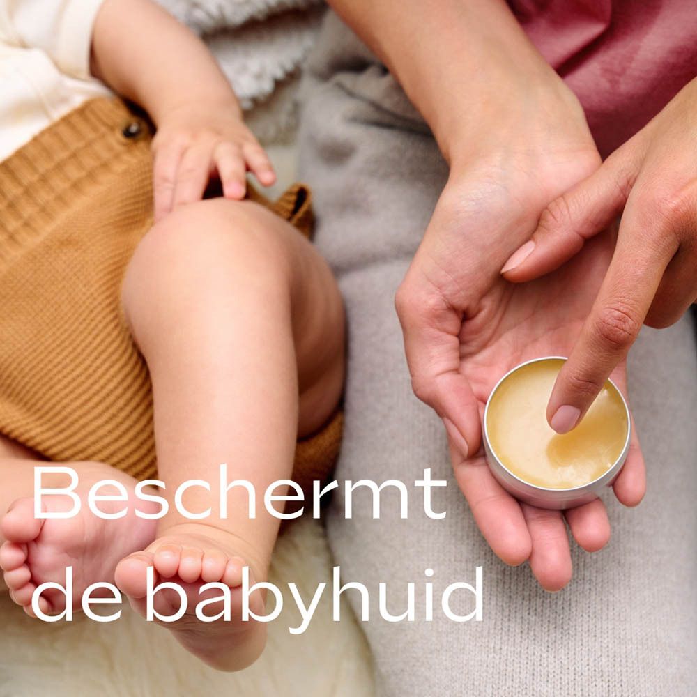 Handen houden een open potje balsem vast. Tekst: Beschermt de babyhuid. Babyvoetjes en -beentjes.