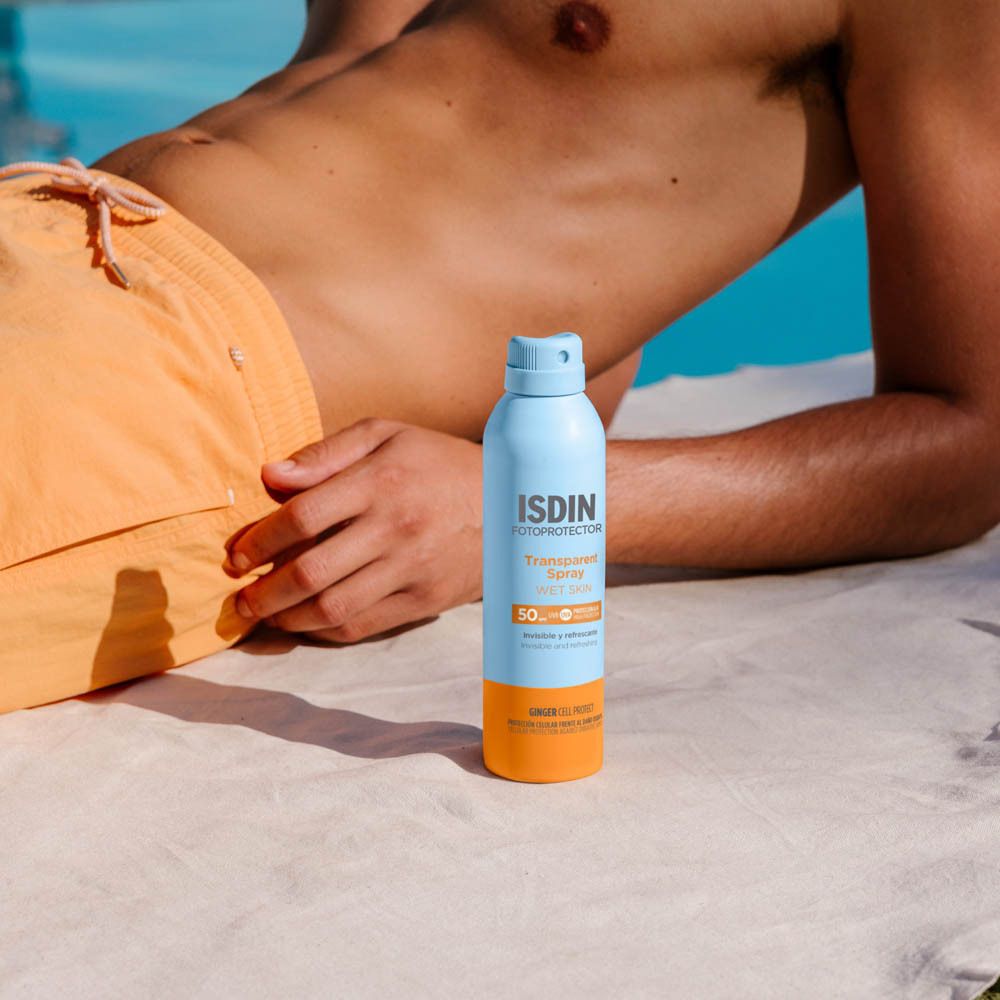 Man bij zwembad. ISDIN Fotoprotector Spray. Fles. Tekst: Transparent Spray Wet Skin SPF50.