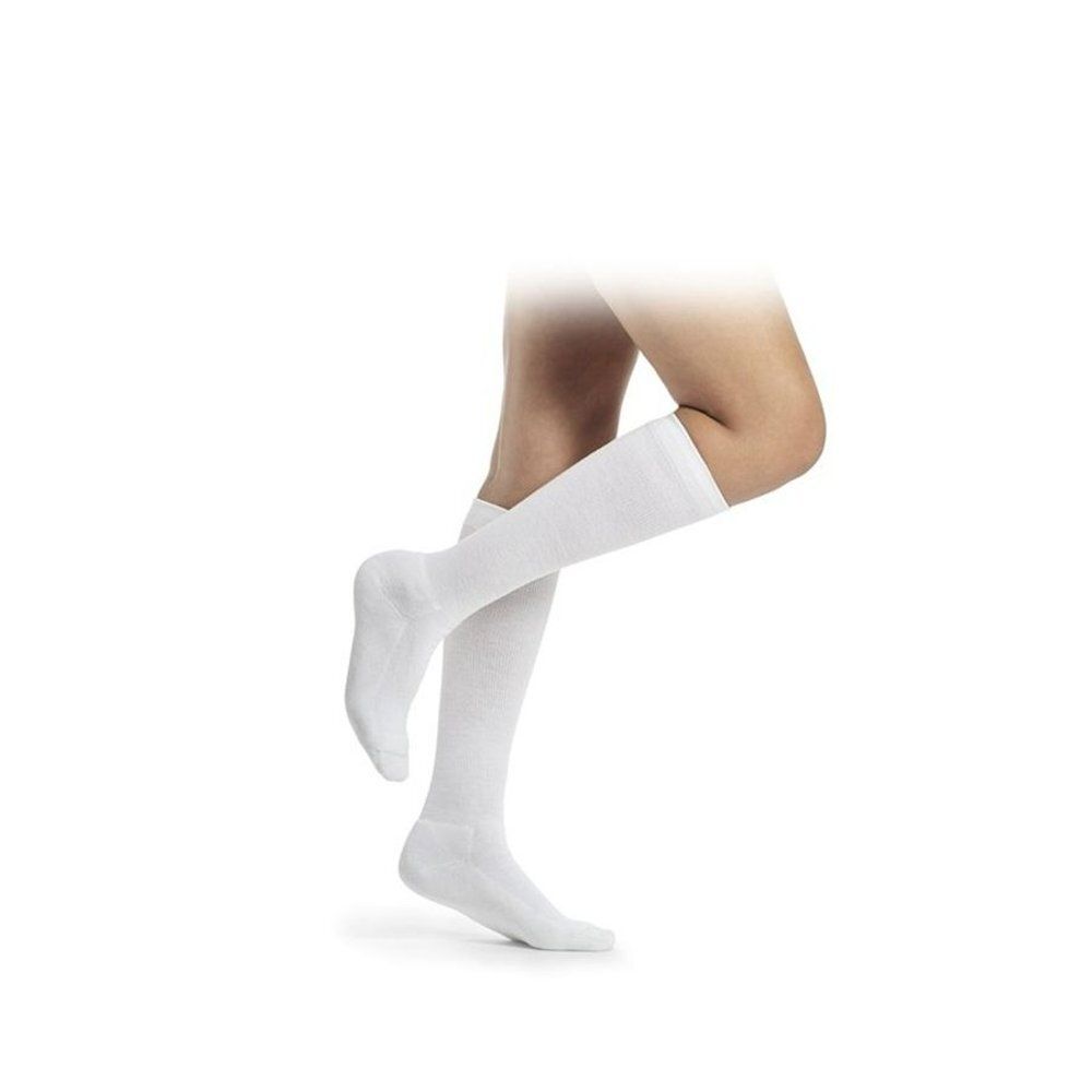 Korte Sigvaris Diabetic compressiekousen voor dames, wit, gedragen op één been. Toont de pasvorm op het onderbeen.