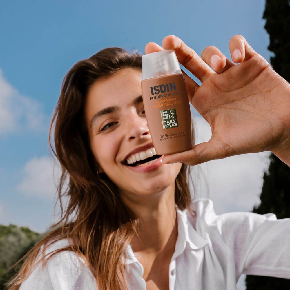 Vrouw houdt ISDIN Fotoprotector FusionWater Magic Bronze vast. Zonnebrandcrème.