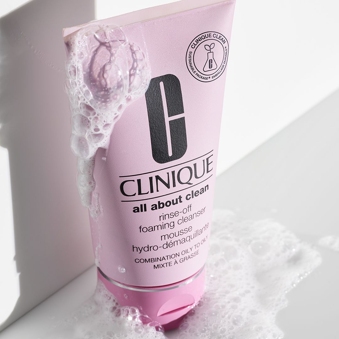 Roze tube met reinigingsschuim. Tekst: CLINIQUE all about clean. Schuim rond de tube.