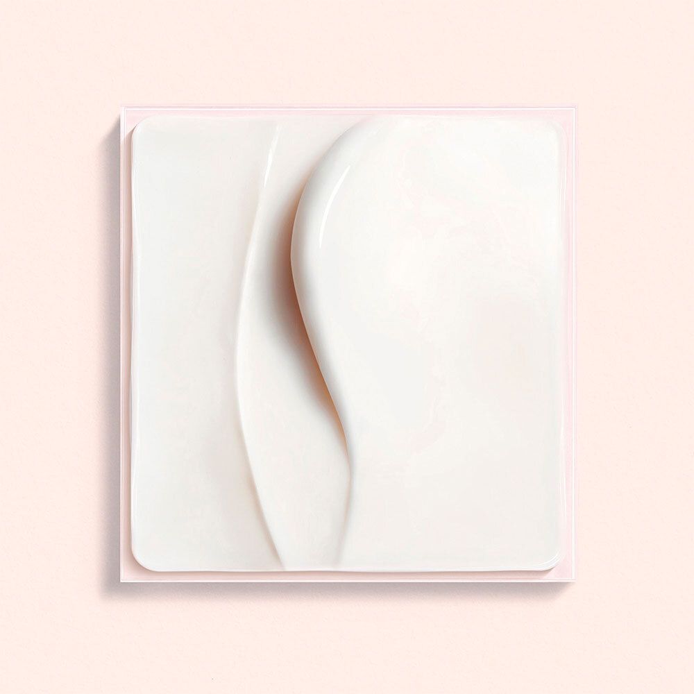 Close-up van een witte crème op roze achtergrond. Crème in vierkante vorm met golvende lijnen.