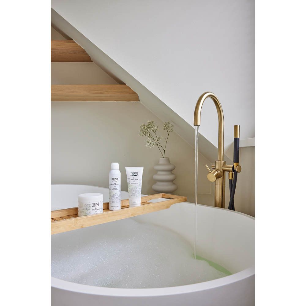 Badkamer met producten. THERME-producten op houten dienblad. Kraan en bad.