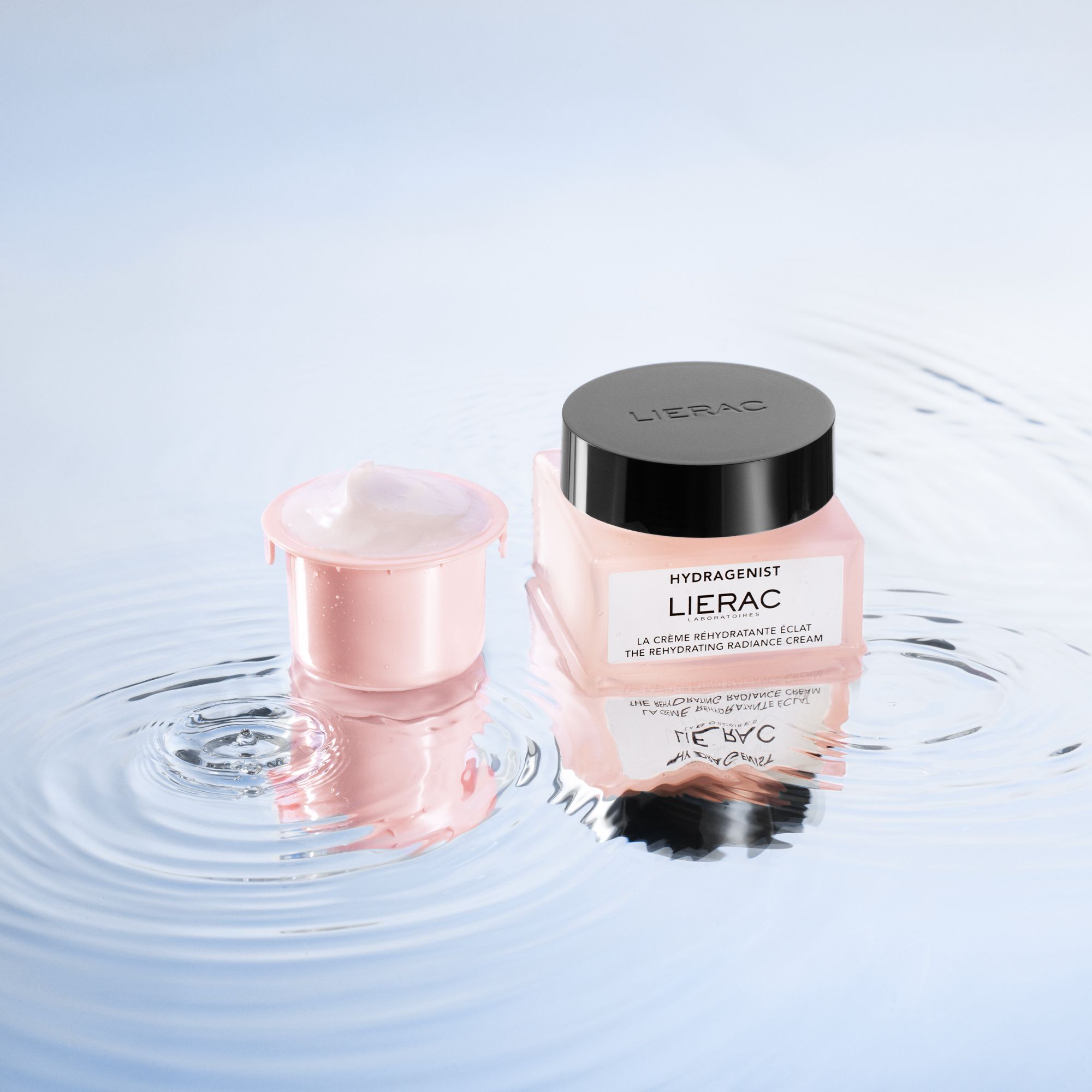 Crèmetiegel en roze container op een reflecterend oppervlak. Merk: LIERAC. Container gevuld met crème.