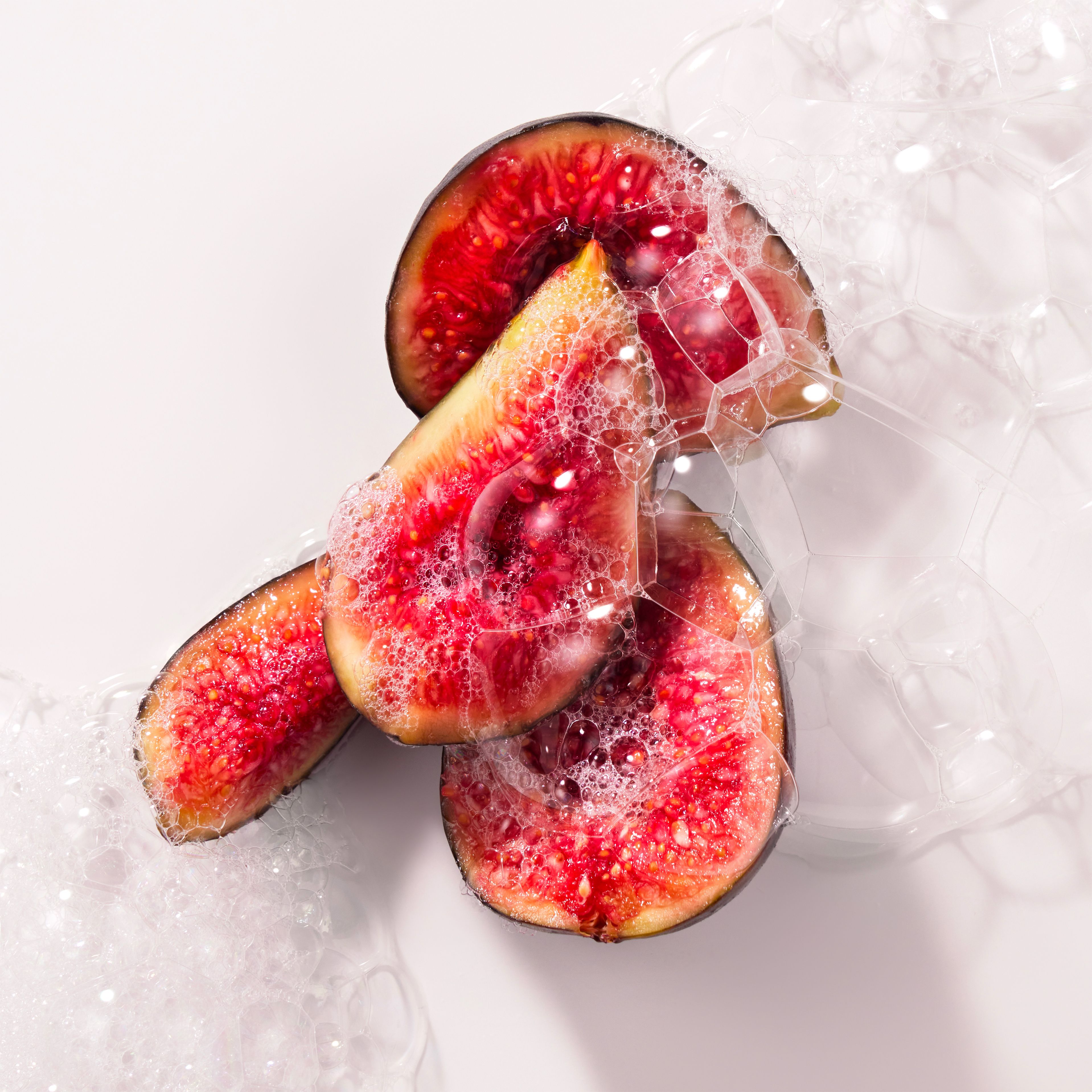 Tranches de figues avec bulles de savon. Gros plan. Tons rouges et roses.