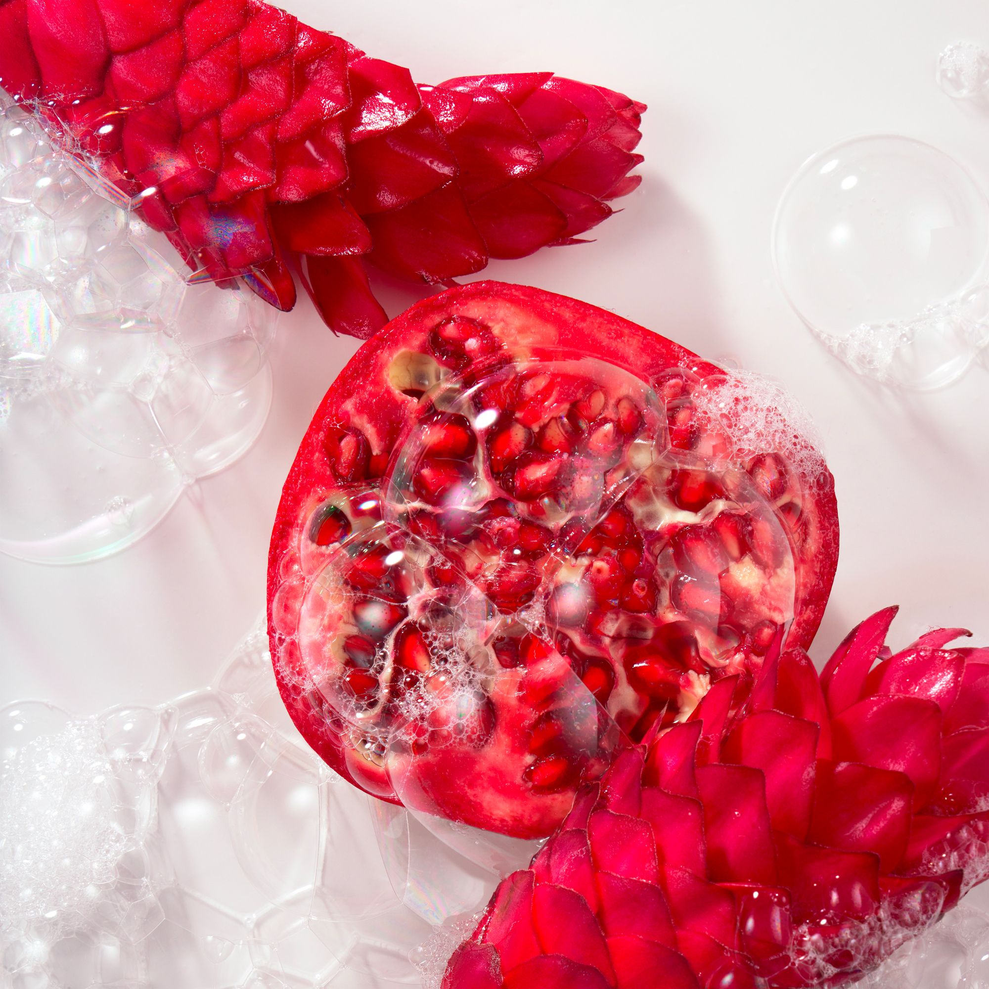 Gros plan de grenade, bulles de savon et fleurs de gingembre. Couleur rouge, environnement clair.