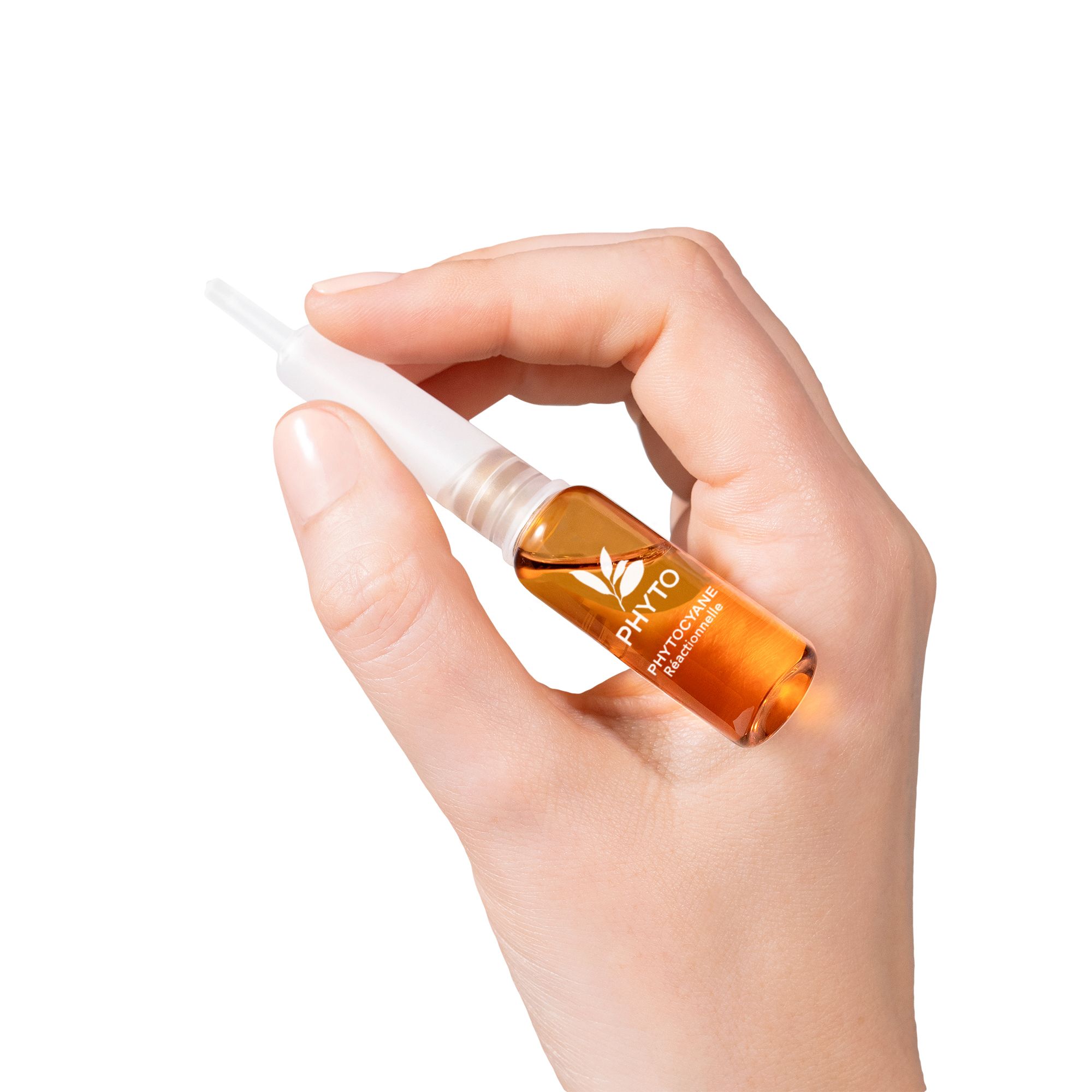 Main tenant une ampoule ambrée avec applicateur blanc. PHYTO est écrit sur l'ampoule.