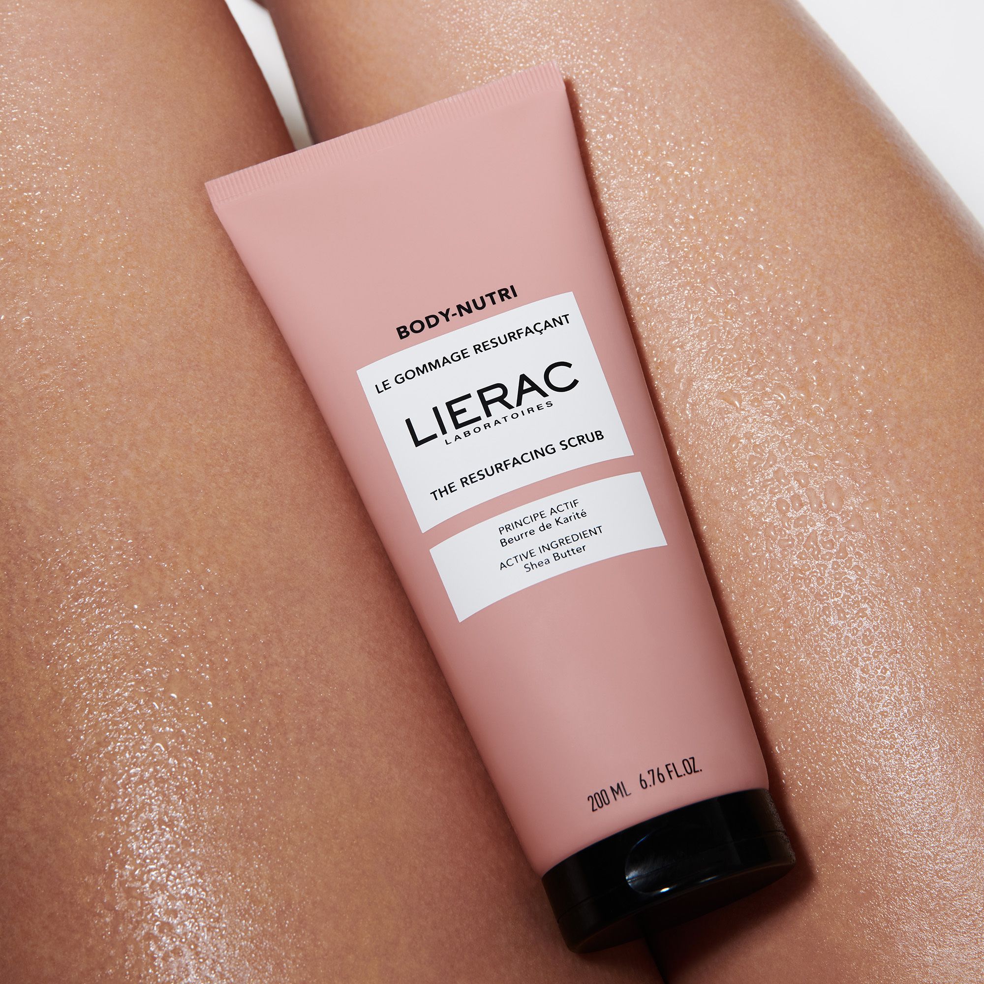 Tube rose avec bouchon noir. Texte: BODY-NUTRI, LE GOMMAGE RESURFAÇANT, LIERAC, THE RESURFACING SCRUB, PRINCIPE ACTIF Beurre de Karité, 200 ml.