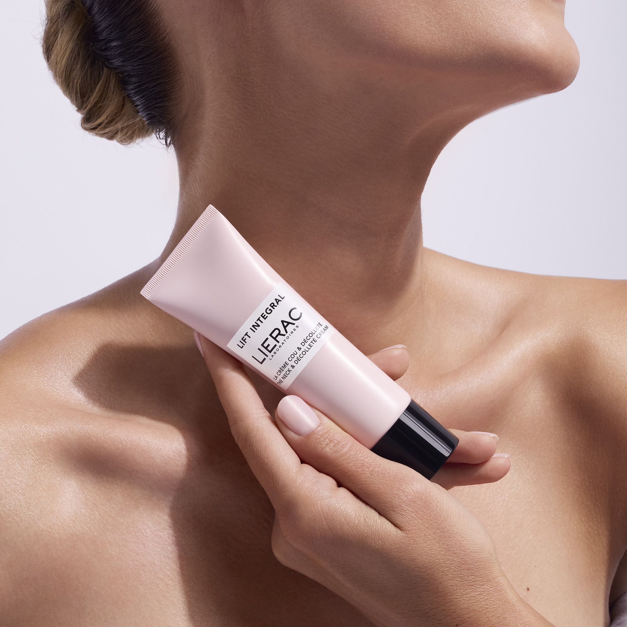 Persoon houdt een roze tube met zwarte dop vast. Opschrift: Lift Integral, Lierac.
