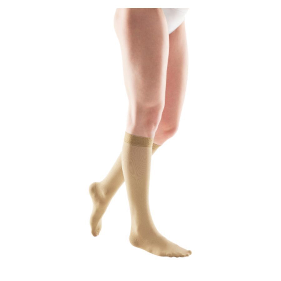 Beige compressiekousen die tot de knie komen. De kousen zijn te zien op een persoon.