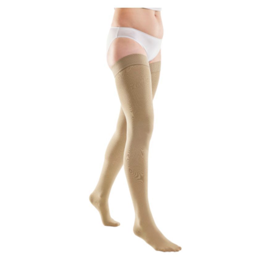 Bas de compression beiges, remontant jusqu'à la cuisse. Motif floral. Porté par une personne. Vue de côté.