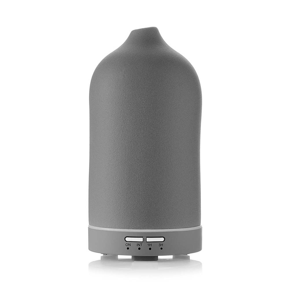 Diffuseur ultrasonique gris, cylindrique, sommet pointu. Panneau de commande avec boutons en bas. Sur fond blanc.