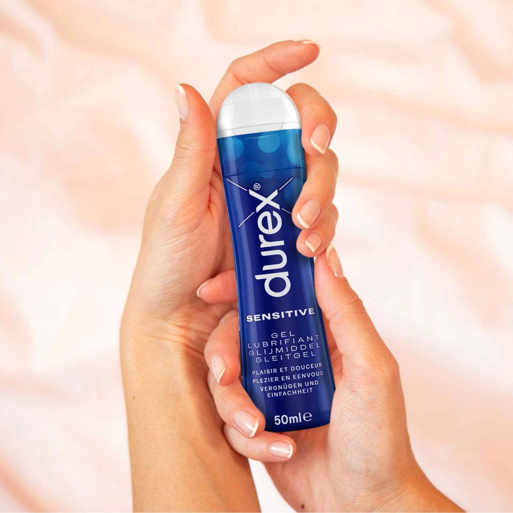 Mains tenant un flacon bleu avec bouchon blanc. Inscription : Durex Sensitive Gel. Volume : 50 ml.