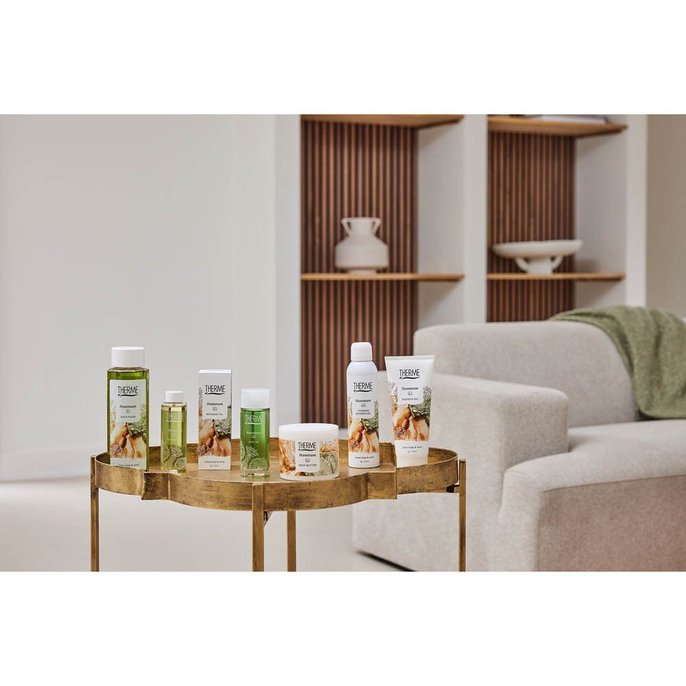 Divers produits THERME sur une table dorée. Dont THERME Hammam BODY BUTTER TO OIL.