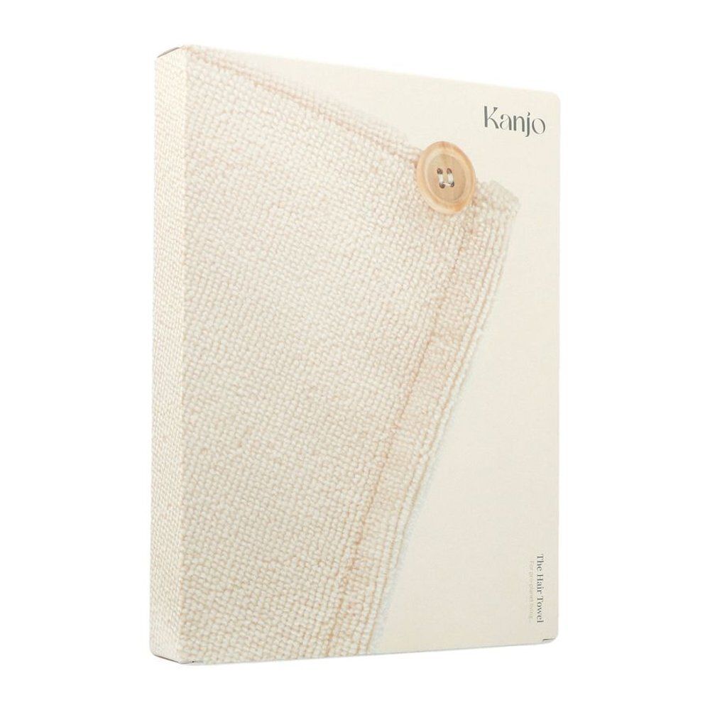 Boîte avec détail d'une serviette crème et bouton. Inscription "Kanjo".