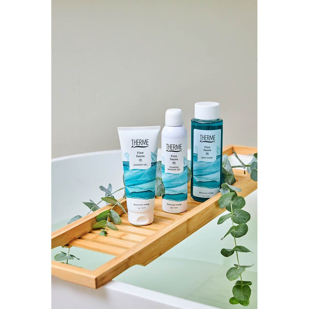 Meerdere THERME Finn Sauna producten, waaronder douchegel, op een houten badplank.