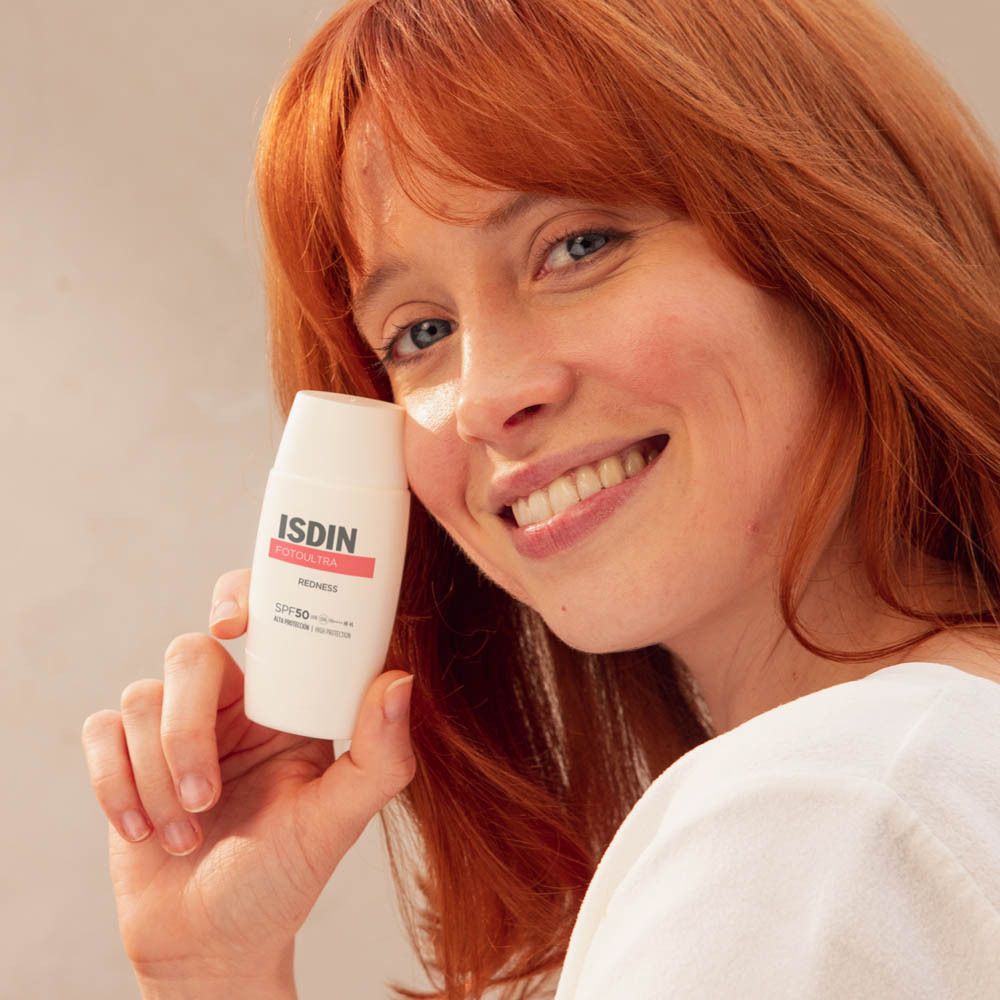 Femme tenant ISDIN FotoUltra Redness. Inscription: SPF 50, Redness.