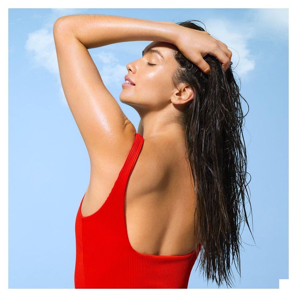 Vrouw met nat haar in rood badpak voor blauwe lucht.